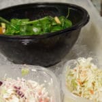 Spinach salad and cole slaw set out for serving a lunch buffet