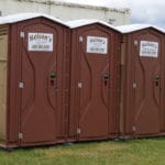 three brown colored porta potties at CACM agility trail, St Cloud MN