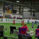 Chairs in front of gating to agility ring; people along side of ring behind 3 ft. high white wall