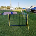 Entry / exit gate to agility ring at easy up tents and dog crates along side of agility ring at East Idaho Fairgrounds-BlackfootID