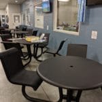 Four black tables with chairs along wall, eating area at Silver Street Park, New Albany IN