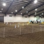 An agility ring on dirt floor with cattle gating, all set up for a FAST course at Lane County Fairgrounds, Eugene OR