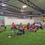 Trial spectators seated at the end of turf area on folding chairs Soccer World, Rochester MN