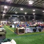 Dog crates lined in rows on turf floor next to the ring Yellow Breeches Sports Center, New Cumberland PA