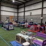 Dog crates and tents lined up on turf floor next to ring Pawsitive Partners, Indianapolis IN