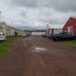 Cars parked in dirt parking lot between buildings at South St. Louis County Fairgrounds, Dirt Floor Arena, Proctor MN