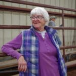 Trial chair Mary Tangren leaning against arena fence at South St. Louis County Fairgrounds, Dirt Floor Arena, Proctor MN
