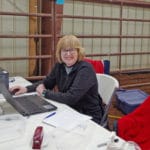 Trial Secretary Jeanne Ahlin sitting at the secretary's table at South St. Louis County Fairgrounds, Dirt Floor Arena, Proctor MN