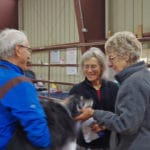 Trial attendees talking and petting one of the dogs beside the crating area at South St. Louis County Fairgrounds, Dirt Floor Arena, Proctor MN