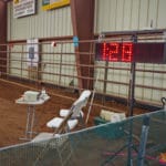 Large digital display of dog's time with table and chairs in front for scribe and timer at South St. Louis County Fairgrounds, Dirt Floor Arena, Proctor MN