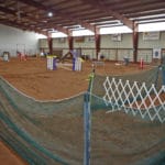 Green mesh construction fencing to make chutes out of agility ring with white folding baby gate on entrance side at South St. Louis County Fairgrounds, Dirt Floor Arena, Proctor MN