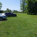 Cars parked on grass with some under large trees at Ann Arbor Dog Training Club, Whitmore Lake MI