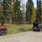 Cars parked in dirt lot beside forest area Camp Li-Wa, Fairbanks AK