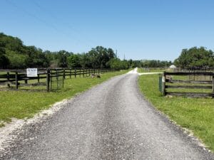 view from road looking down grave driveway to paw's n que's