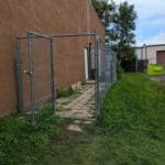 tall narrow chain link fence with gate around exit door to potty area at forest city dog training club in love's park il